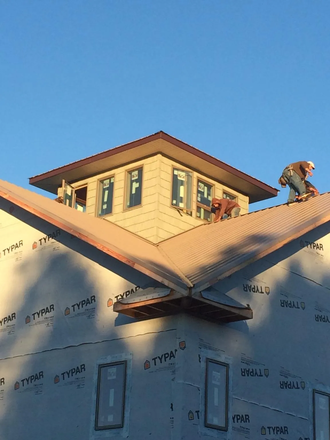 Roofers working around a rooftop cupola on a new metal roof at sunset — Roof Waterproofing in Kingston by Roofing Brothers